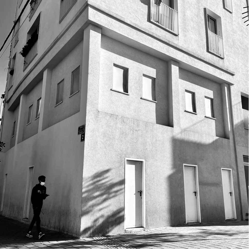 נער חולף על פני חזית חנויות אטומה בפינת הרחובות סלומון וארלנג׳ר. שכונת נווה שאנן, תל אביב-יפו 